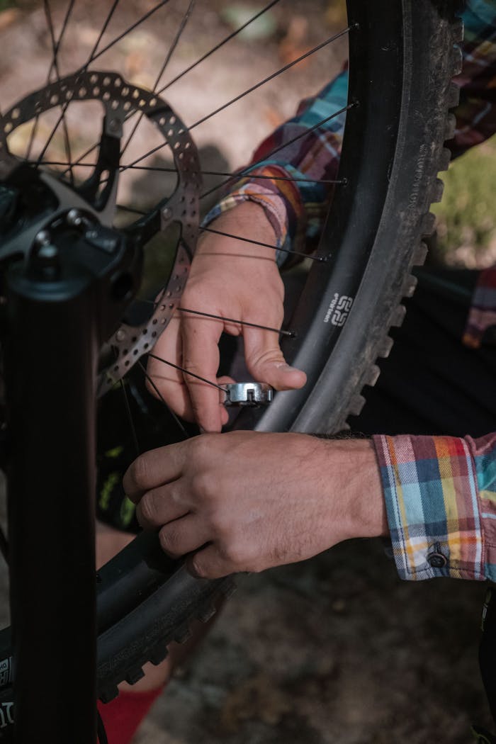Hands adjusting a bicycle wheel outdoors, focusing on mechanics and cycling maintenance.